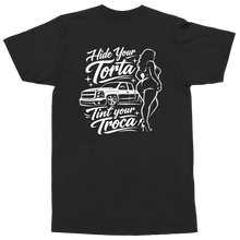 Load image into Gallery viewer, A black short-sleeve t-shirt with a white graphic print on the back. The graphic features the text 'Hide Your Torta Tint Your Troca' in a stylized cursive font, accompanied by a white line-art illustration of a pickup truck and a woman in a bikini.
