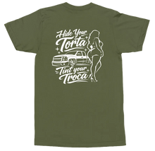Load image into Gallery viewer, An olive green short-sleeve t-shirt shown from the back, featuring a white graphic print of a car, a pin-up style woman, and the text 'Hide Your Torta, Tint Your Troca'.

