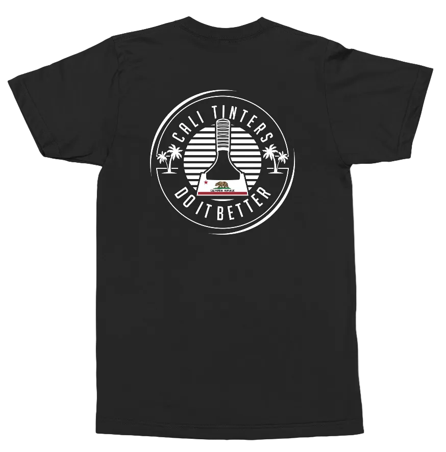 A black short-sleeve t-shirt shown from the back, featuring a large white circular graphic print on the center back with a bottle illustration, palm trees, and the text 'CALI TINTERS DO IT BETTER'.