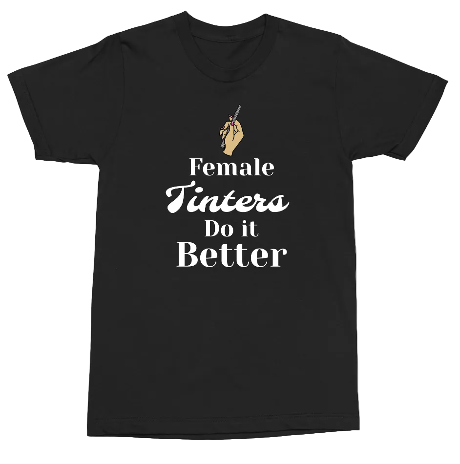 A black short-sleeve crewneck t-shirt with a graphic print on the front. The graphic features a small tan illustration of a hand holding a paintbrush above the text 'Female Tinters Do it Better' in white and tan lettering, displayed on a clean white background.