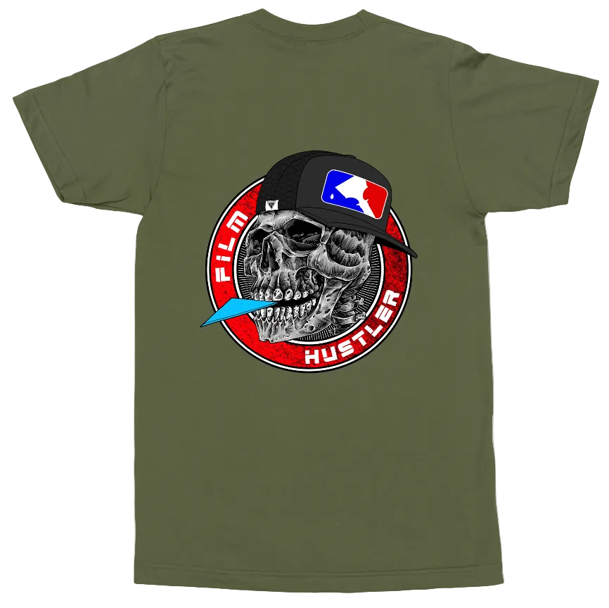 An olive green short-sleeve t-shirt with a large graphic print on the front. The graphic features a black baseball cap with a red, white, and blue flag logo, worn by a detailed black and white skull.