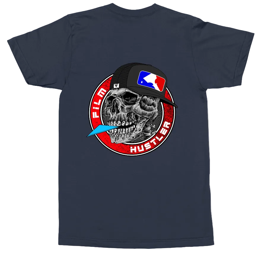 A navy blue short-sleeve t-shirt with a large graphic print on the front. The graphic features a detailed black and white skull wearing a black baseball cap with a red and blue flag logo, surrounded by a red circular emblem with the text 'FILM HUSTLER' and a small blue feather detail.