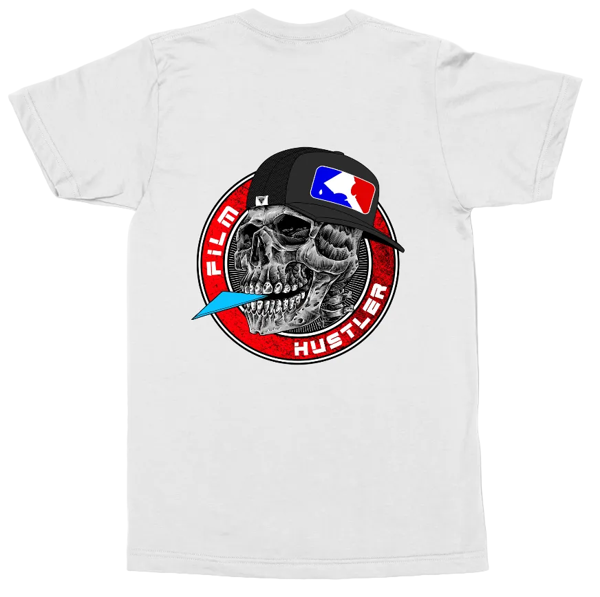 A white short-sleeve t-shirt shown flat against a white background, featuring a large graphic print on the back. The graphic depicts a skull wearing a black baseball cap with a red, white, and blue flag logo, inside a red circular emblem with the words 'FILM HUSTLER' and a blue feather accent.