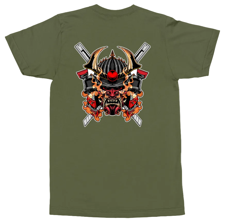 An olive green short-sleeve t-shirt shown flat against a white background, featuring a large graphic print on the back of a samurai helmet with crossed swords and flames.