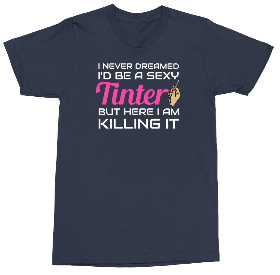 A navy blue short-sleeve t-shirt with a graphic text print on the front. The text reads 'I NEVER DREAMED I'D BE A SEXY Tinter BUT HERE I AM KILLING IT' in white and pink lettering, with a small hand graphic holding a phone.