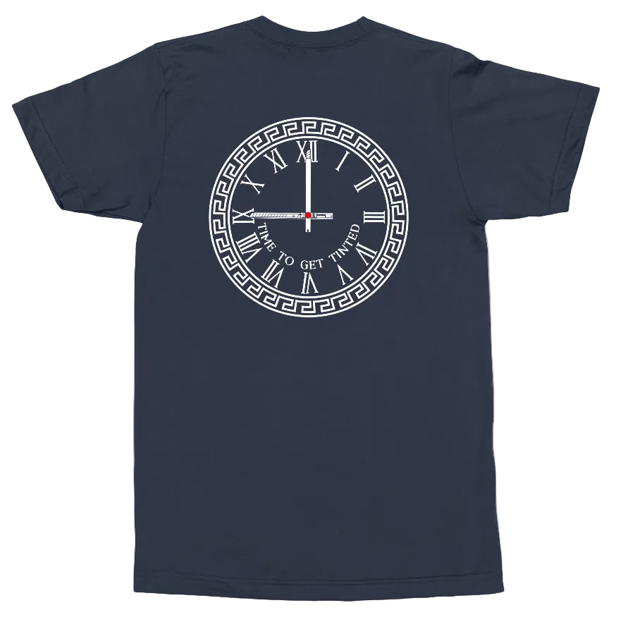 A navy blue short-sleeve t-shirt shown from the back, featuring a white graphic of a clock with Roman numerals, a Greek key border, and the text 'TIME TO GET INVITED' in the center.