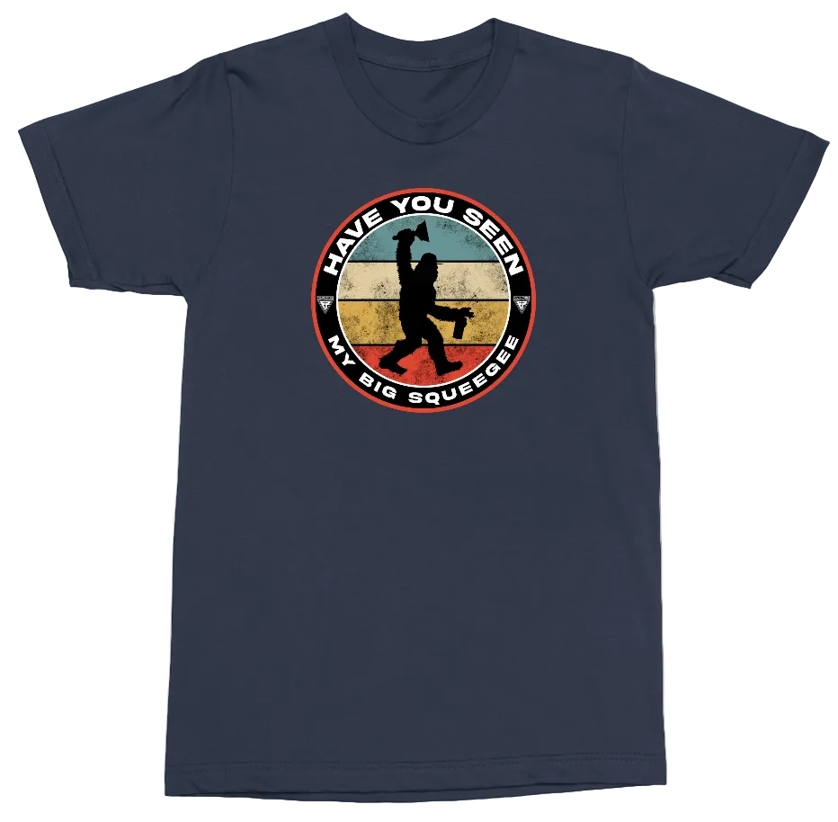 A navy blue short-sleeve t-shirt with a circular graphic on the chest. The graphic features a distressed, retro-style background in shades of blue, beige, and red, with a black silhouette of a person holding a hammer and the text 'HAVE YOU SEEN MY BIG SQUEEZE'.