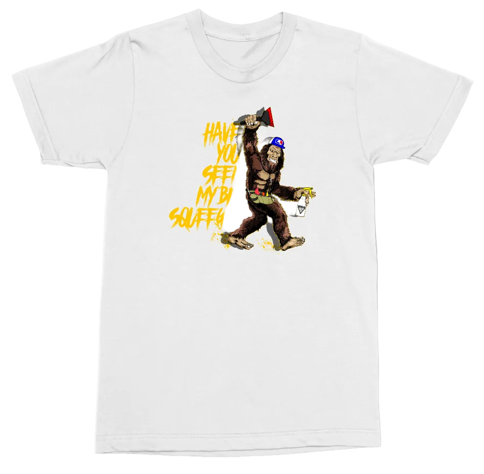 A white short-sleeve crewneck t-shirt featuring a colorful graphic print of a cartoon Bigfoot-like figure holding a megaphone and spray paint can, with yellow text reading 'HAVE YOU SEEN MY BIG SQUEEGEE'.