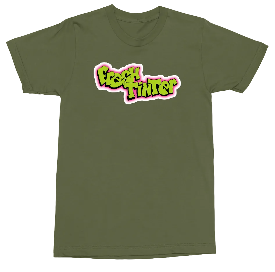 An olive green short-sleeve t-shirt with a colorful graphic on the chest reading 'Fresh Tinted' in a stylized neon font with pink and white outlines.