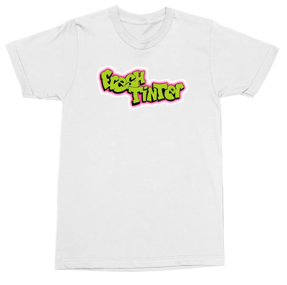 A white short-sleeve crewneck t-shirt featuring a colorful graphic on the chest that reads 'FRESH TINTED' in a bubbly, 3D-style font with a bright pink and lime green color scheme.