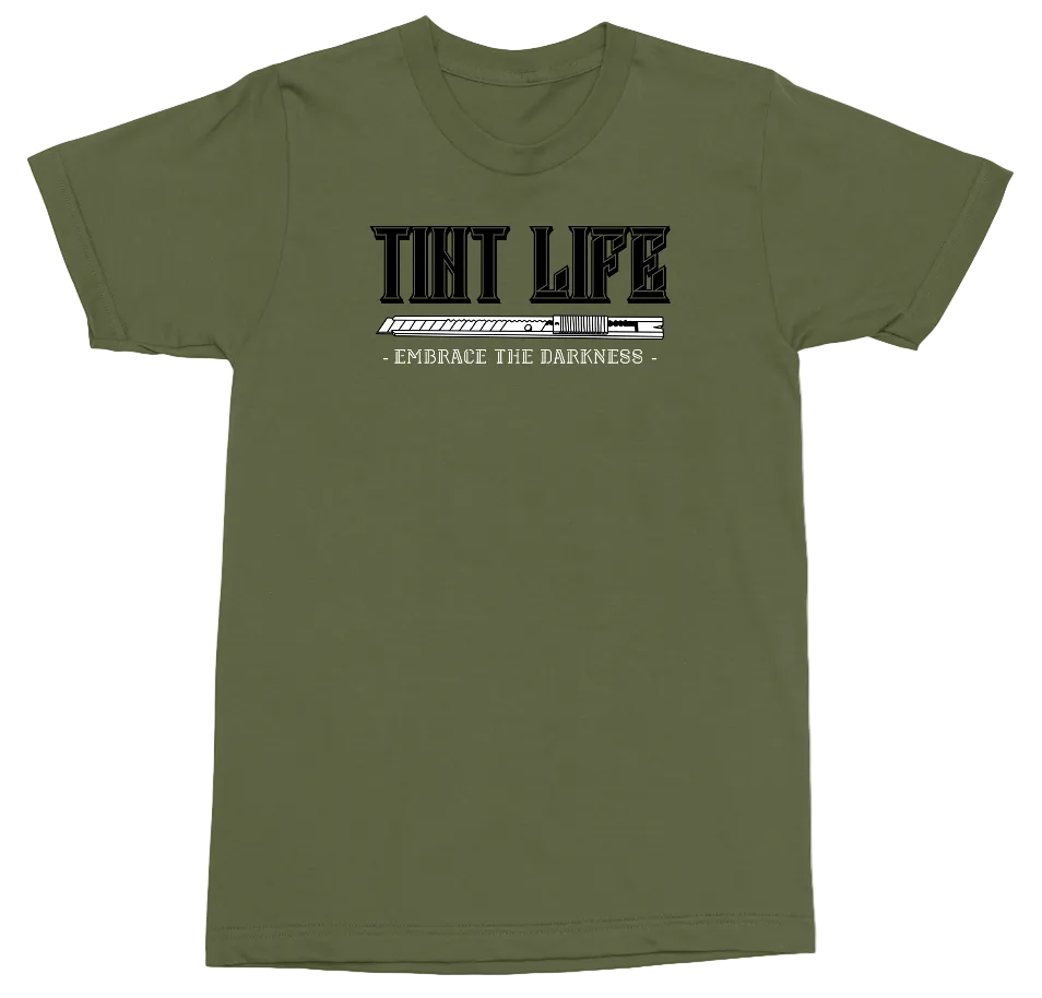 An olive green short-sleeve t-shirt with a black graphic print on the chest reading 'TINT LIFE' and 'EMBRACE THE DARNNESS' below it, displayed on a clean white background.