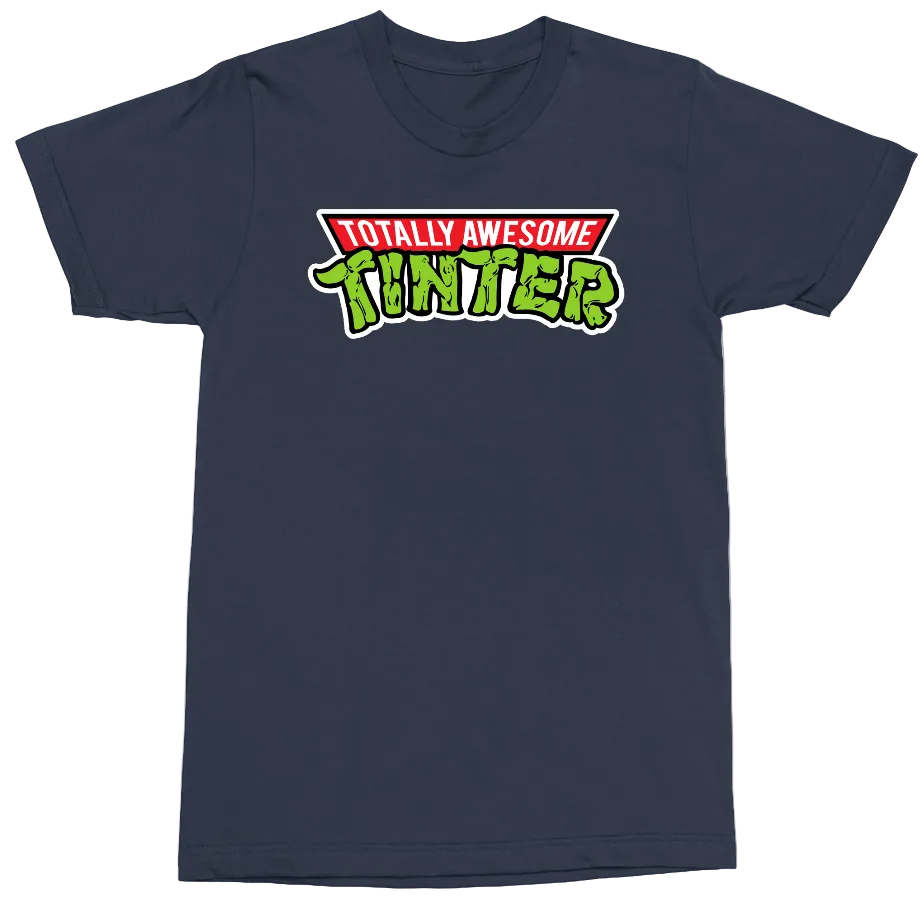 A navy blue short-sleeve crewneck t-shirt featuring a retro-style graphic on the chest that reads 'TOTALLY AWESOME TINTERS' in red, white, and green.